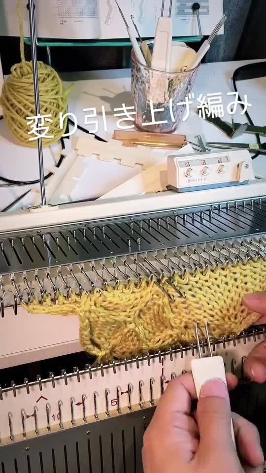 黄色の編み地の目を引き上げる手元